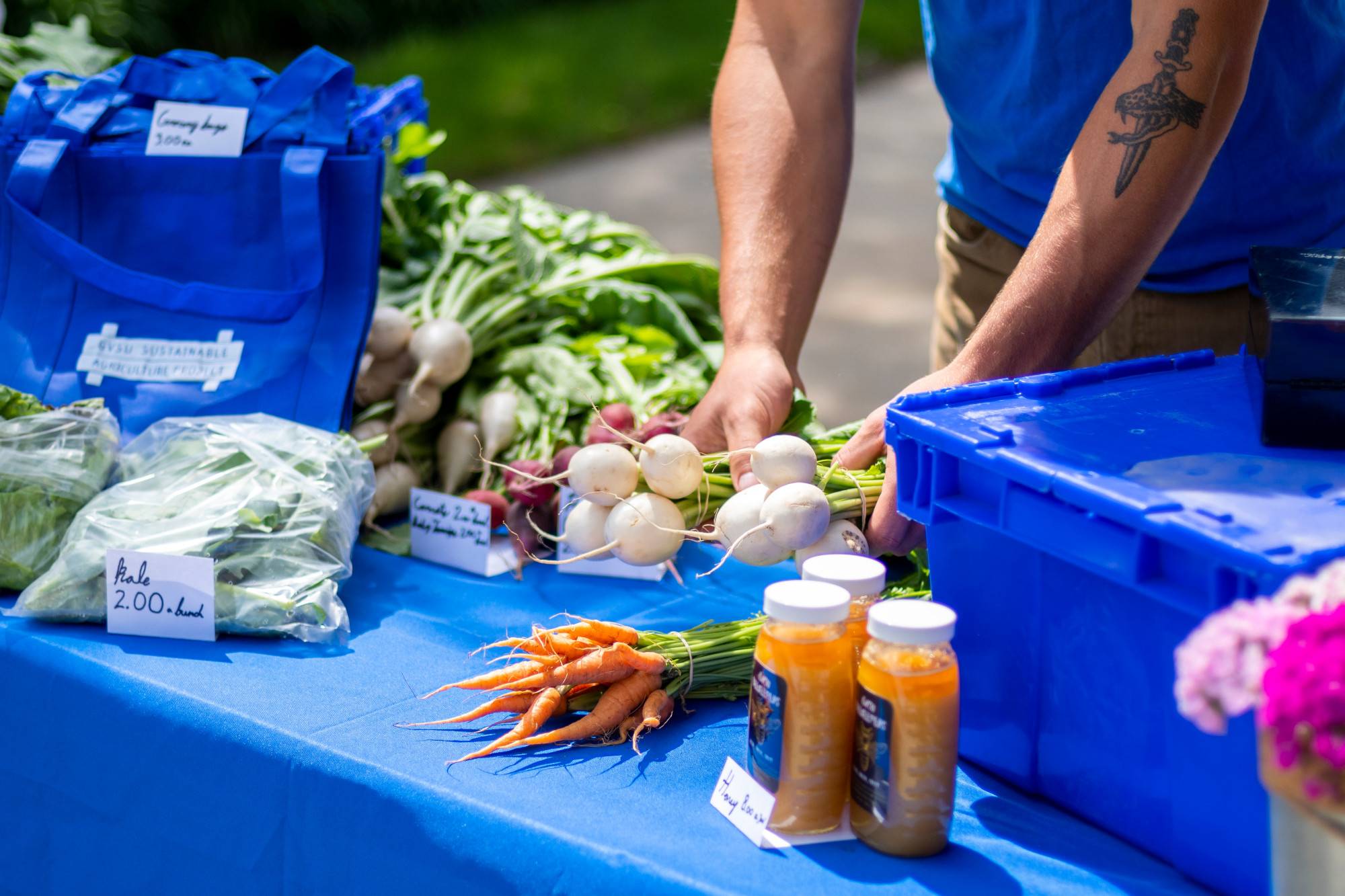 A table at the Farmers Market holding veggies that were grown on the Sustainable Agriculture Project farm at GVSU, and honey from the GVSU Beekeepers Club